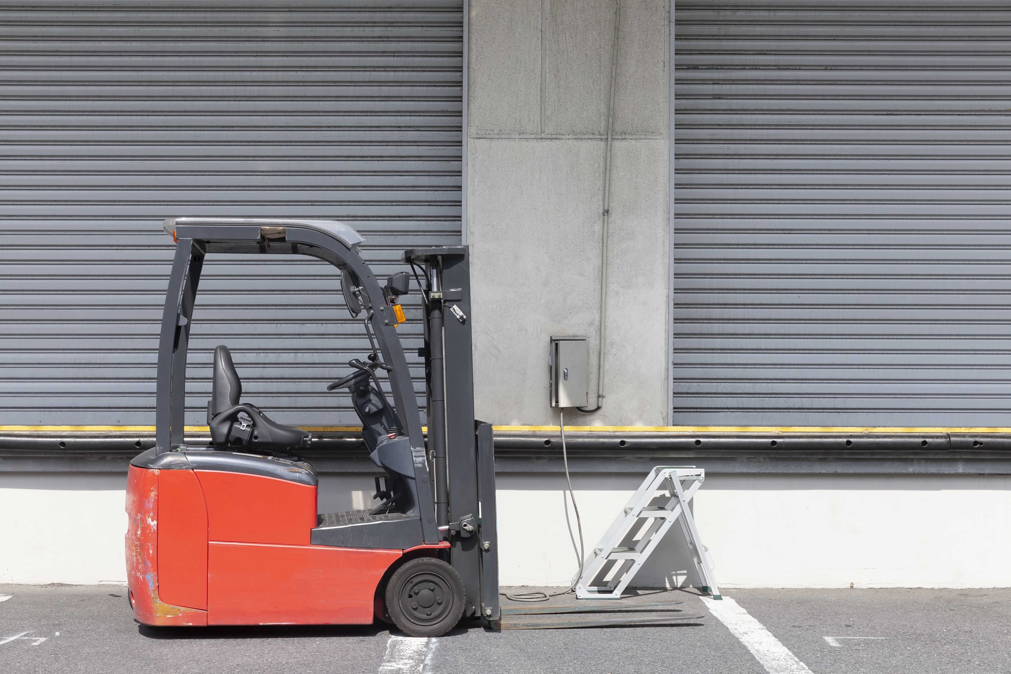 A forklift is parked in front of a warehouse in the industrial area